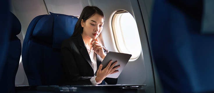 Woman on plane reading on her tablet