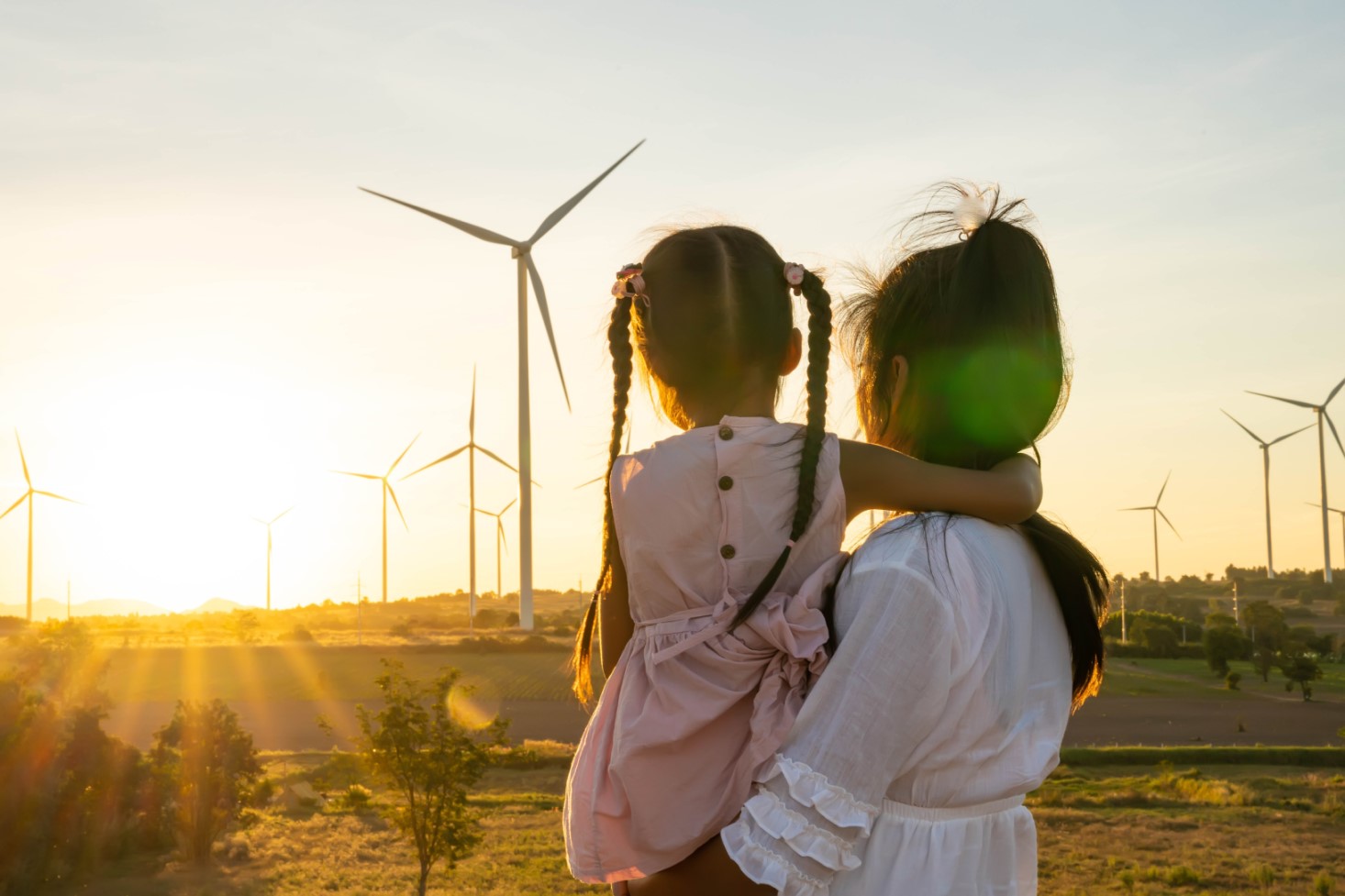 Woman carrying a child looking at windmills 