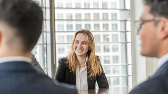 A person smiling at a table with other people in the background