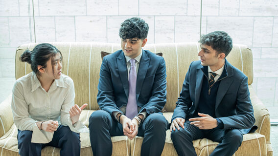 three students talking on a sofa