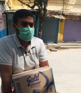 man wearing mask, carrying box