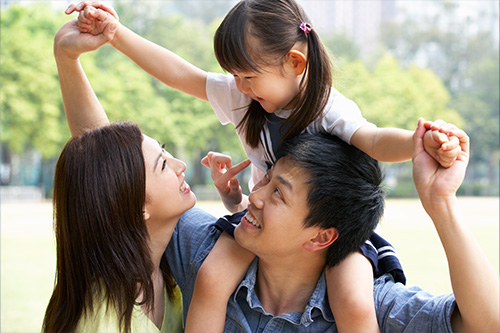 A family play together in a park. We provide banking products for all life stages.