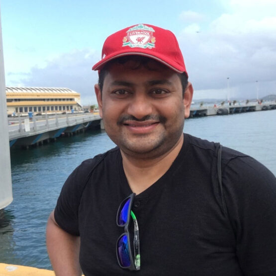 Tanmay Sahay standing in front of lake wearing a red cap