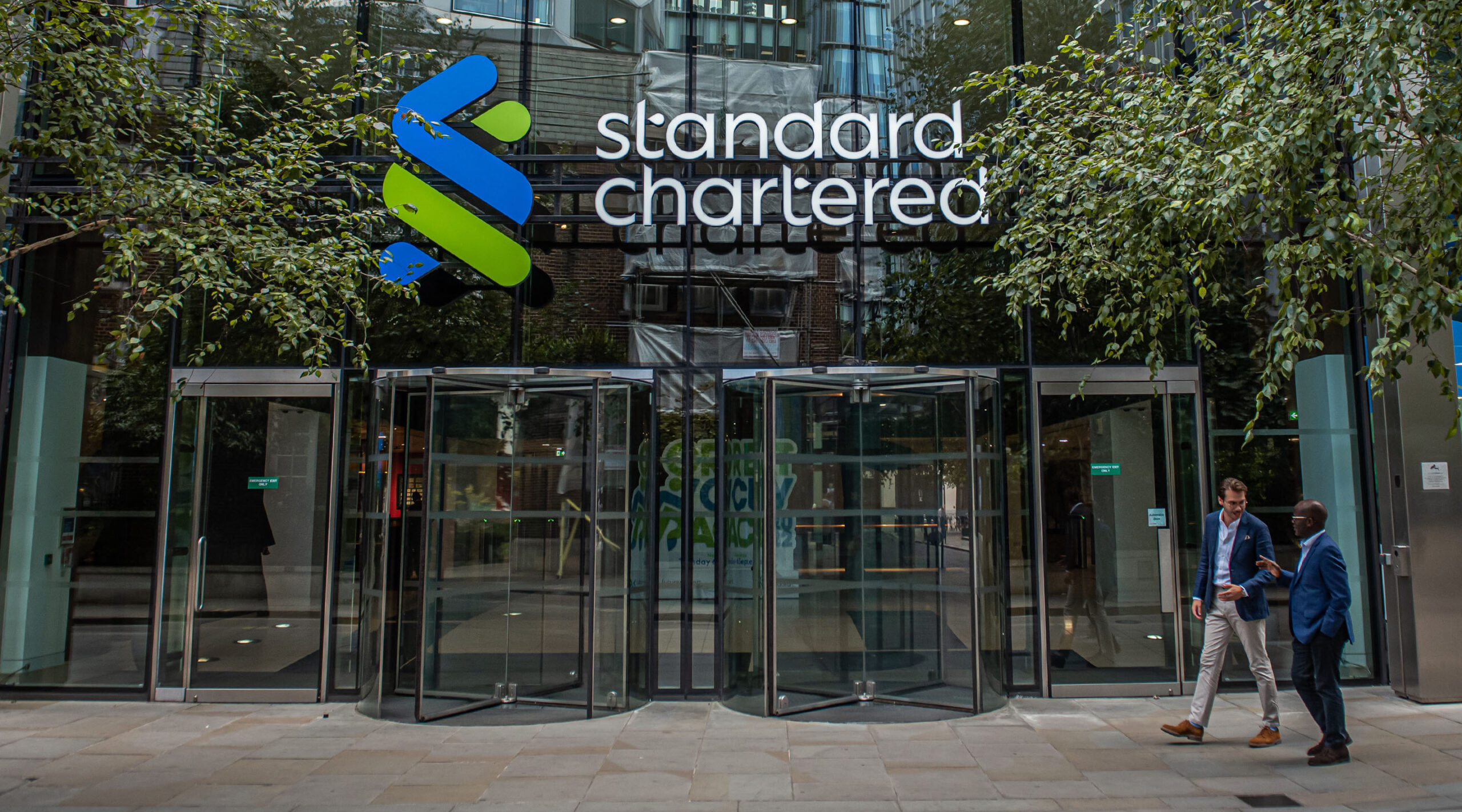 Two colleagues walk outside the London HQ of Standard Chartered.