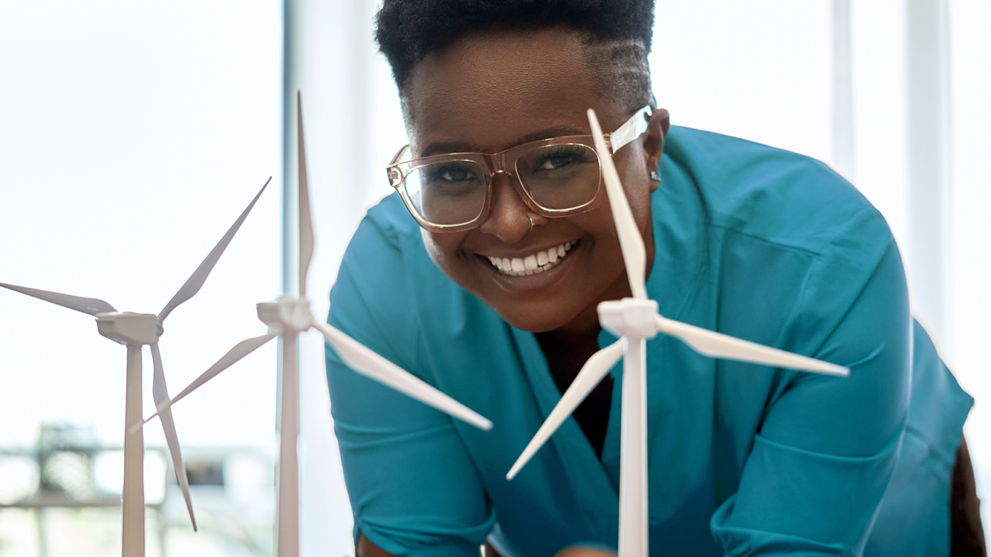 A woman smiles in front of some model wind turbines.