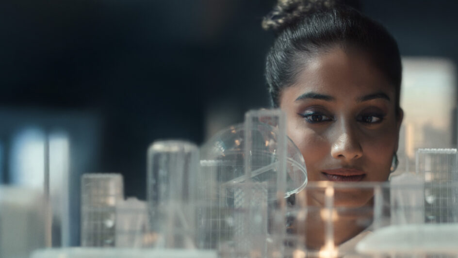 A woman gazes at a city skyline while holding a lit candle, creating a serene and contemplative atmosphere.