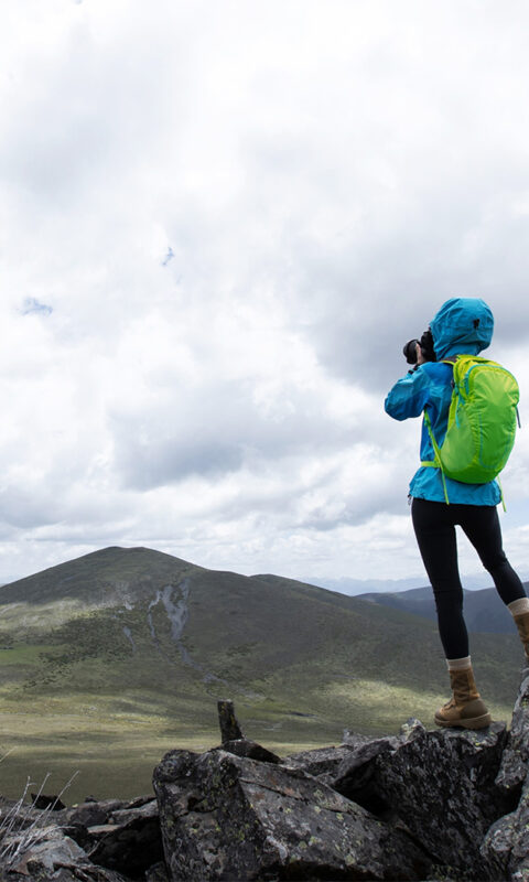 a photographer stands on a rocky hilltop