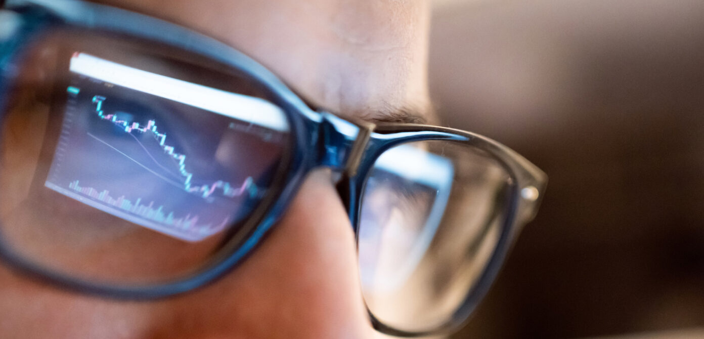 Closeup of a person's face with glasses reflecting a screen of the market