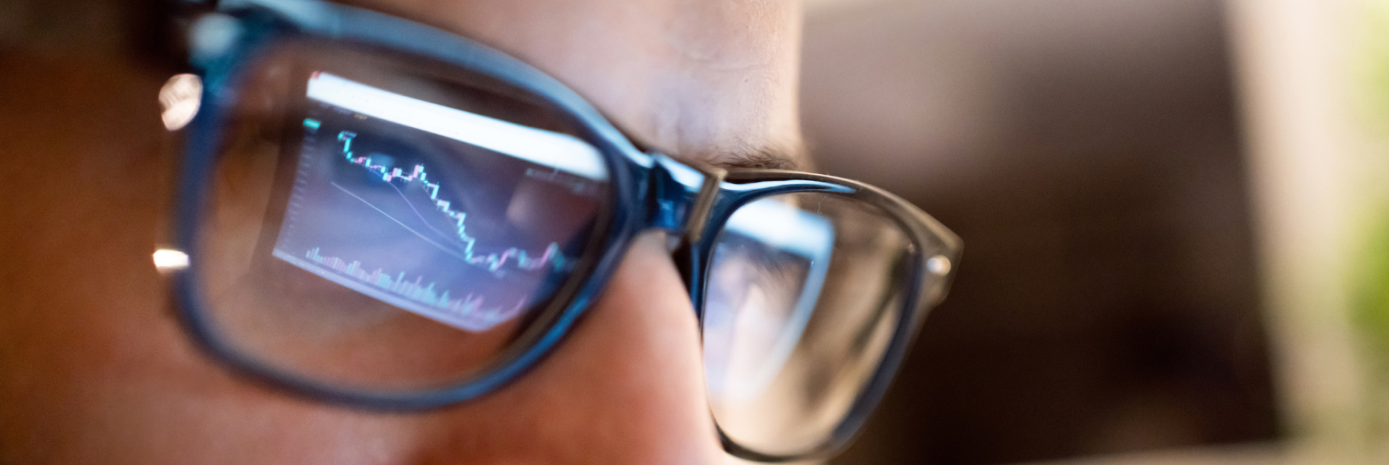 Closeup of a person's face with glasses reflecting a screen of the market