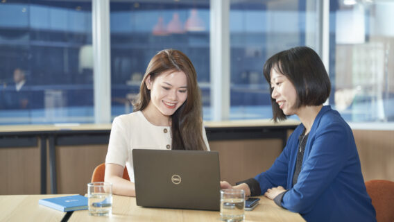 Two women looking at a laptop, discussing work in an office set up