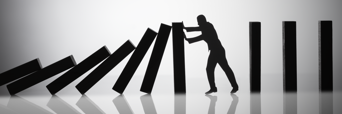 Businessman holding up falling dominoes