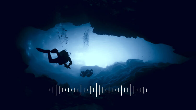 divers swimming in underwater cave