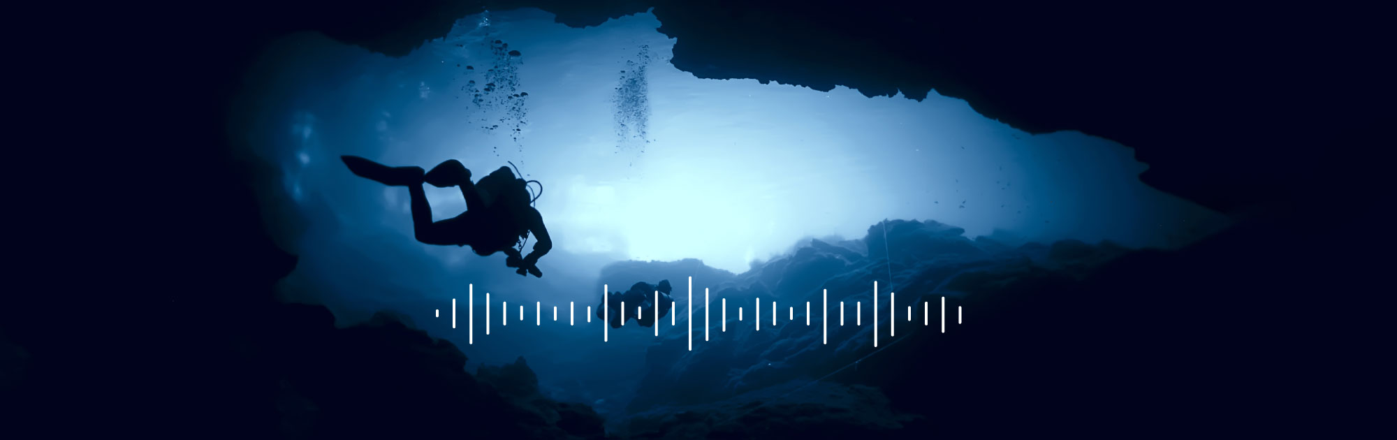 divers swimming in an underwater cave