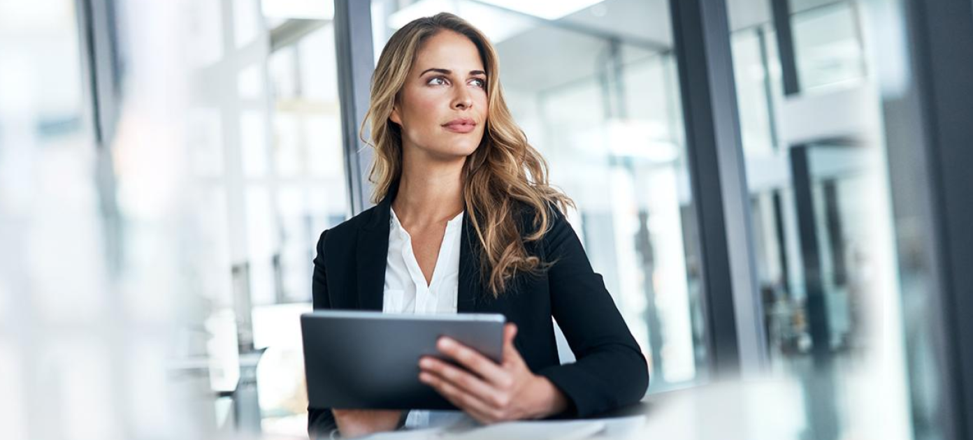 A woman in a black blazer and white shirt, holding an ipad masthead