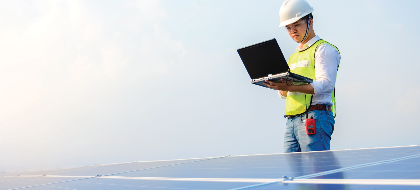 A man holding a laptop with solar panels in front