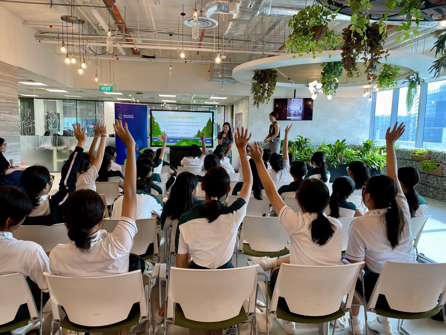 A group of woman raise their hands in a session to ask questions to the speaker