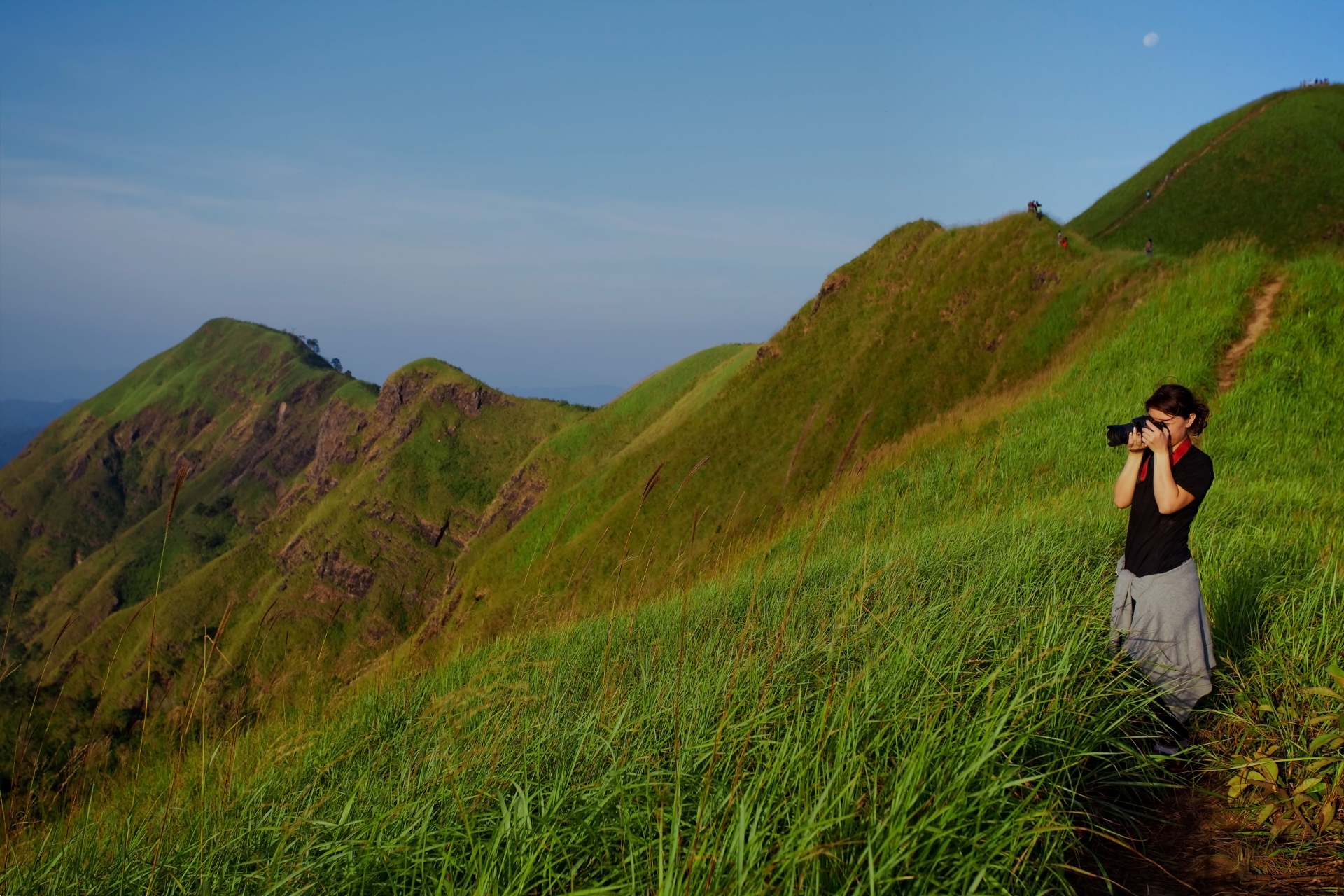 A girl taking photos on the green mountains