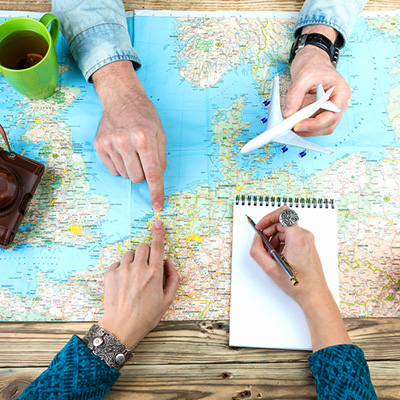Two people planning the trip with world map, plane model and notebook