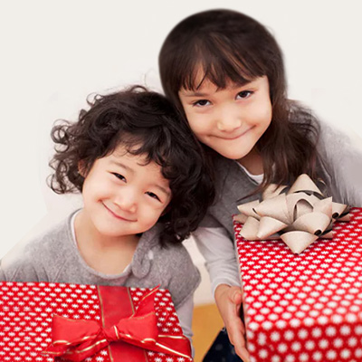 Two kids are smiling and holding the red gift box