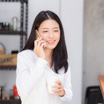 a lady talking on phone, while holding a coffee cup on hand