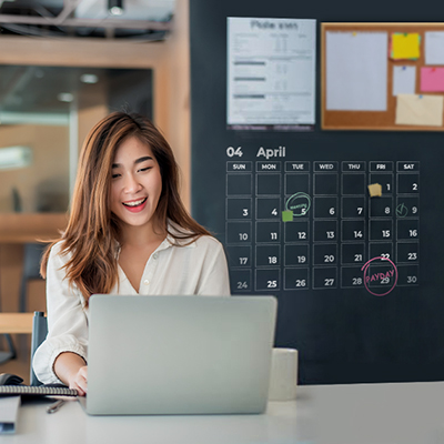 lady using laptop in office setting, a calendar with payday circled in red