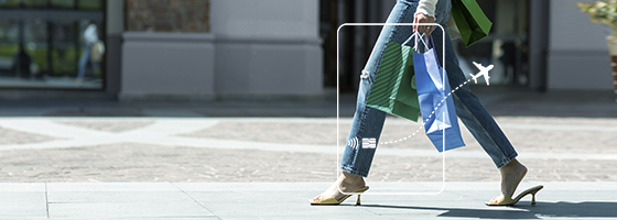 Woman in jeans walking in a relaxing way, her hands holding shopping bags