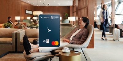 Man relaxing in the airport lounge; Standard Chartered Cathay Mastercard - Priority Banking card face