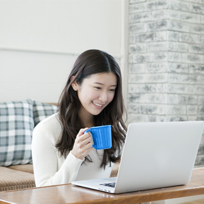 a lady enjoying Standard Chartered online banking investment services while drinking with a mug
