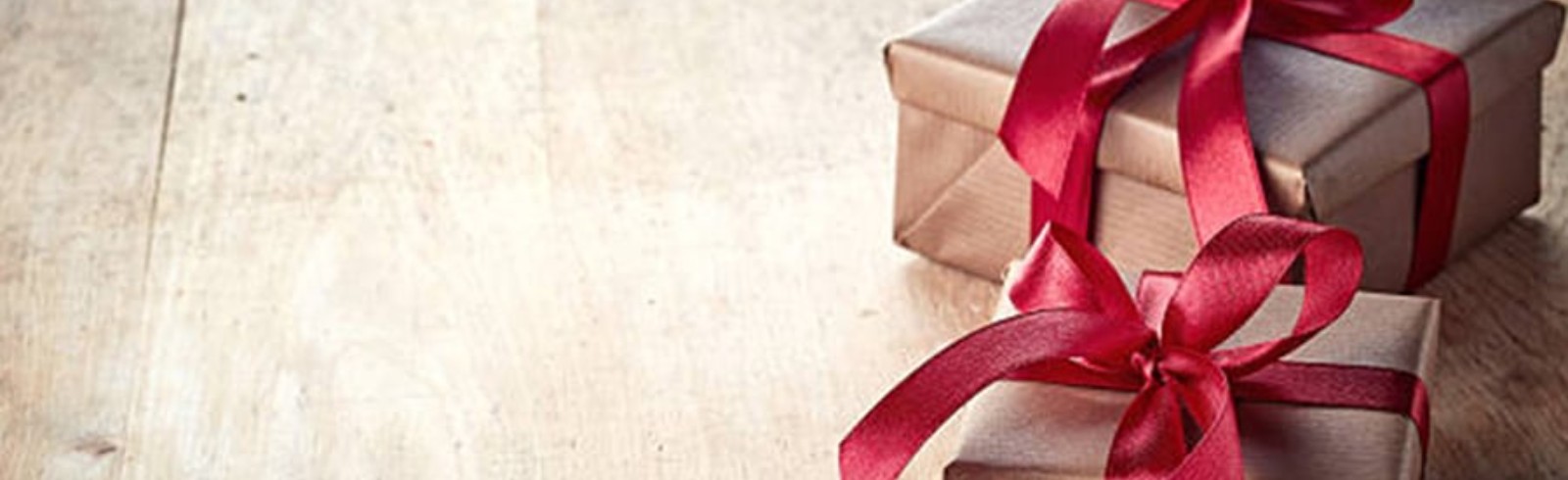 2 gift wrapped by brown papers and red ribbon on the wooden floor
