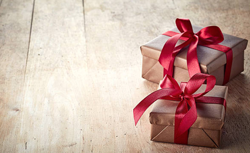 2 gift wrapped by brown papers and red ribbon on the wooden floor