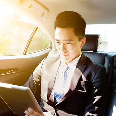 a businessman in a car, checking employee payroll data on Straight2Bank diskette with tablet