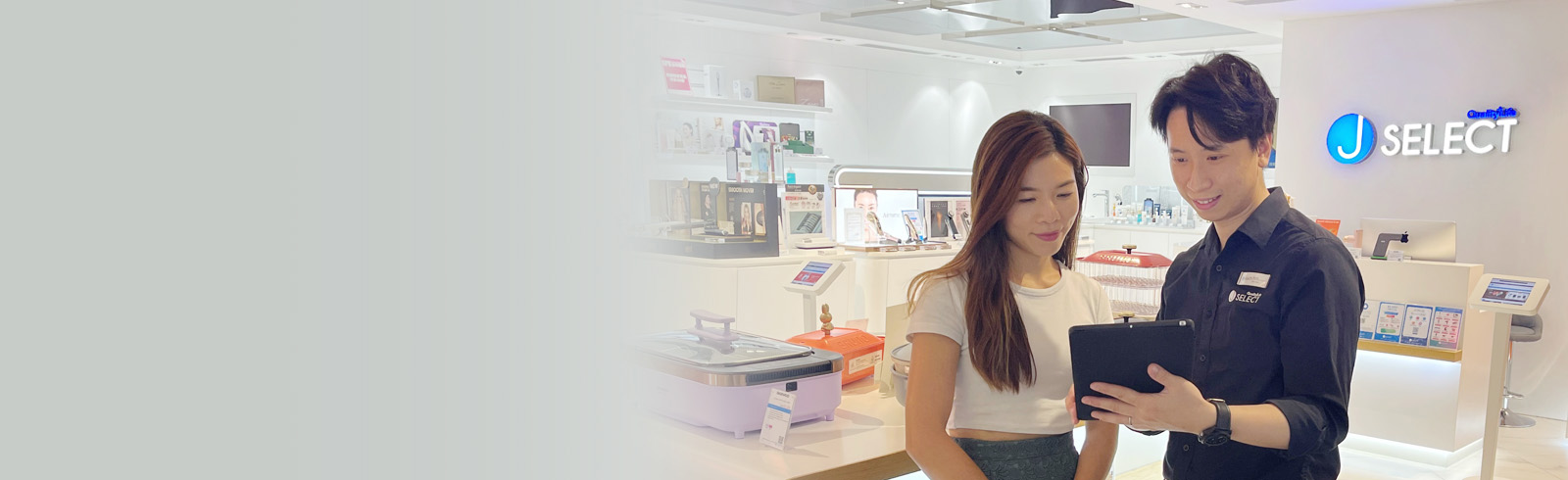 一名身穿黑色袖衫的營業員正在使用他手上的平板電腦在J Select店舖向女士推銷產品