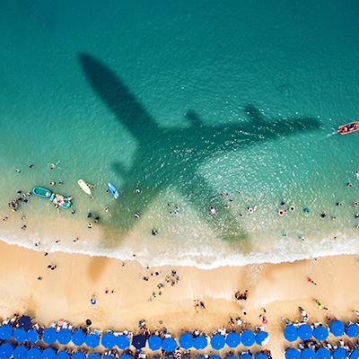 飛機的影子投射在陽光明媚、人多的海灘上
