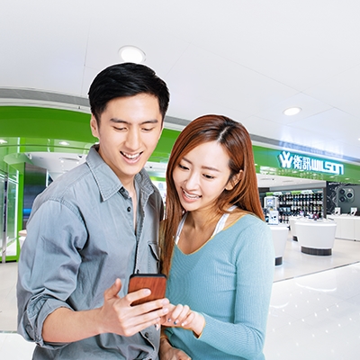 一對情侶站在衛訊的商店前使用他們的手機