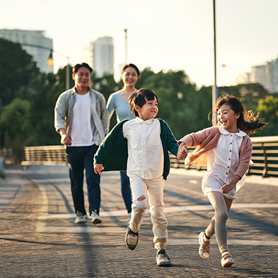 Happyasianfamilywithtwochildrenwalkingonpedestrianbridge