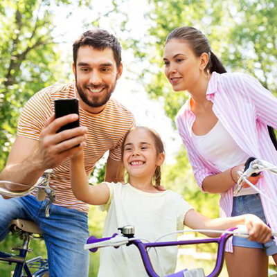 Family with smartphone and bicycles in summer park