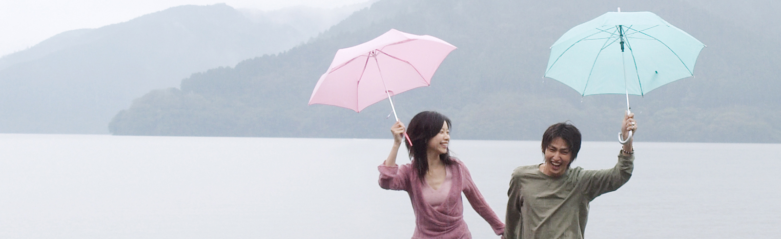 Couple holding an umbrella in the rain laughing