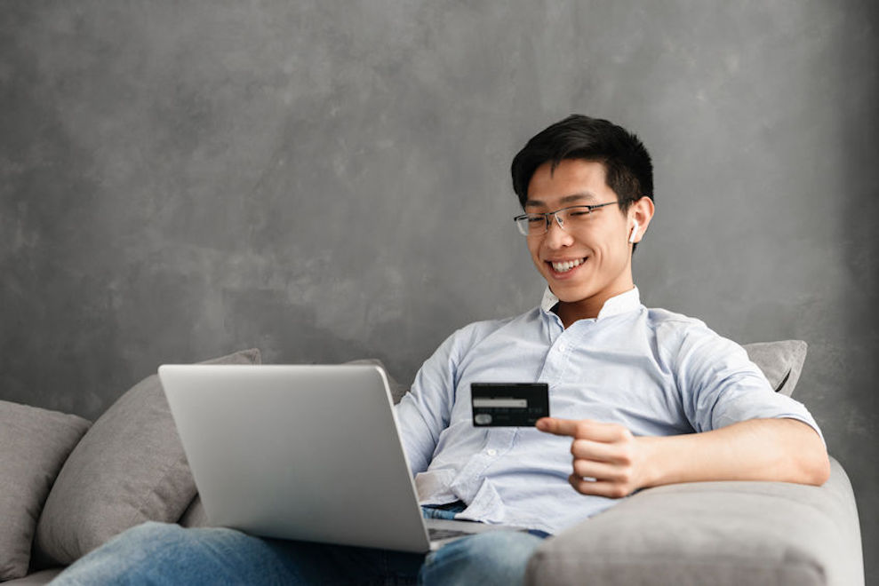 Happy young asian man using laptop