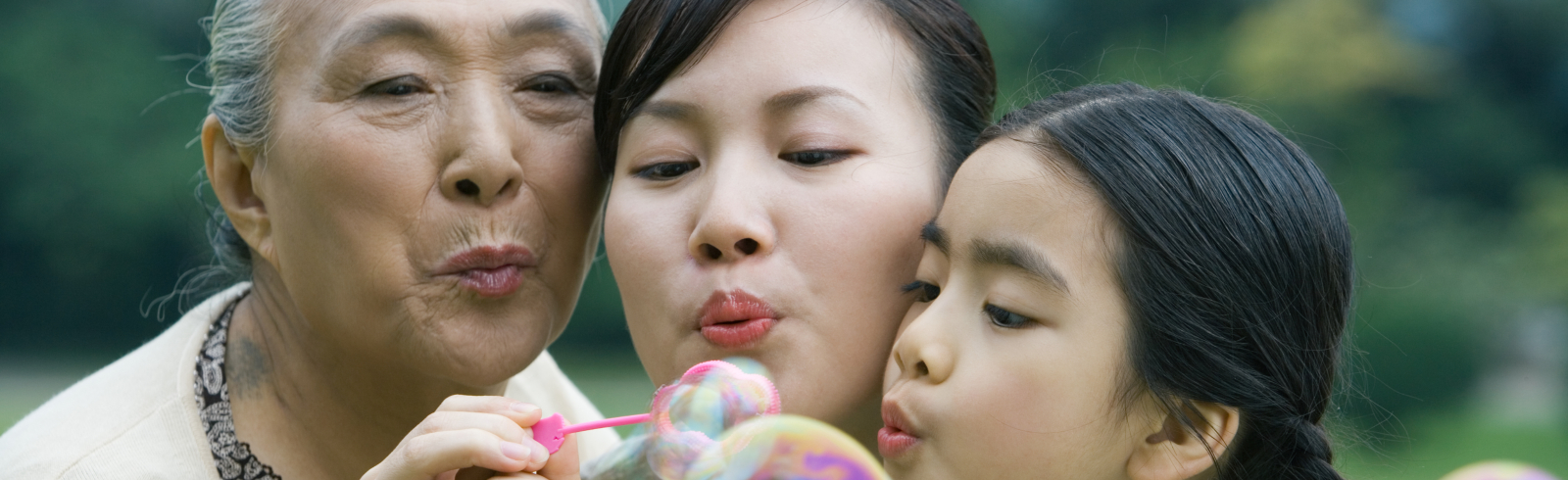 Three generations - grandmother, mother and granddaughter - blowing bubbles together